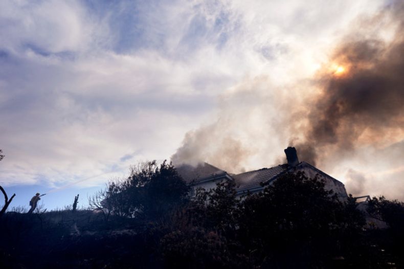 Un bombero trabaja para extinguir el fuego en una casa envuelta en llamas por el incendio Norte, el viernes 16 de octubre de 2026, en San Juan Capistrano, California. (AP Foto/Jae C. Hong)
