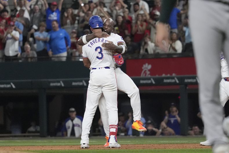 El dominicano de los Rangers de Texas, Leody Taveras (3) es abrazado por su compañero de equipo, el cubano Adolis García luego de conectar un sencillo con bases llenas para remolcar a Ezequiel Durán en el noveno episodio y ganar el juego de béisbol ante los Atléticos de Oakland, el sábado 31 de agosto, de 2024, en Arlington, Texas. (AP Foto/LM Otero)