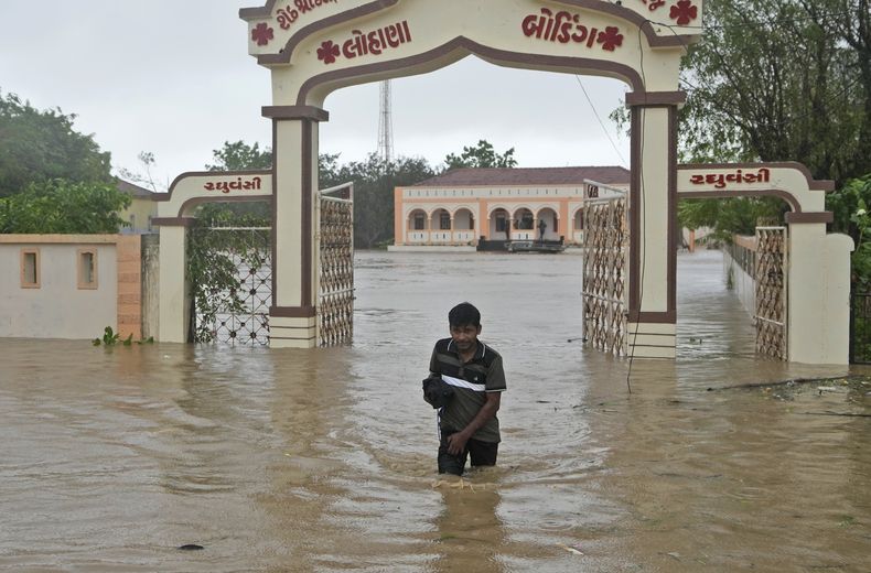 Un hombre camina por una calle anegada por las precipitaciones tras el paso del ciclón Biparjoy por Mandvi, en el distrito de Kutch, en el estado de Gujarat, en el oeste de India, el 16 de junio de 2023. (AP Foto/Ajit Solanki)