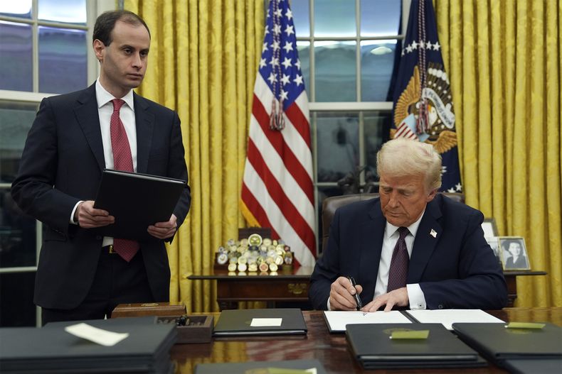 El presidente Donald Trump firma una orden ejecutiva para crear el Departamento de Eficiencia Gubernamental (DOGE) en el Despacho Oval de la Casa Blanca, el lunes 20 de enero de 2025, en Washington, mientras el secretario de despacho de la Casa Blanca, Will Scharf, observa. (AP foto/Evan Vucci)