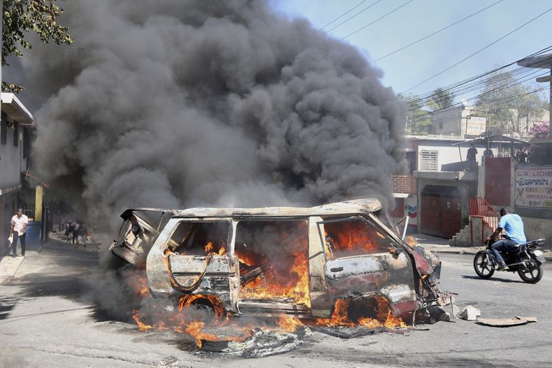 Un motociclista pasa frente a un auto en llamas durante una protesta contra la inseguridad en Puerto Príncipe, Haití, el miércoles 2 de abril de 2025. (AP Foto/Odelyn Joseph)