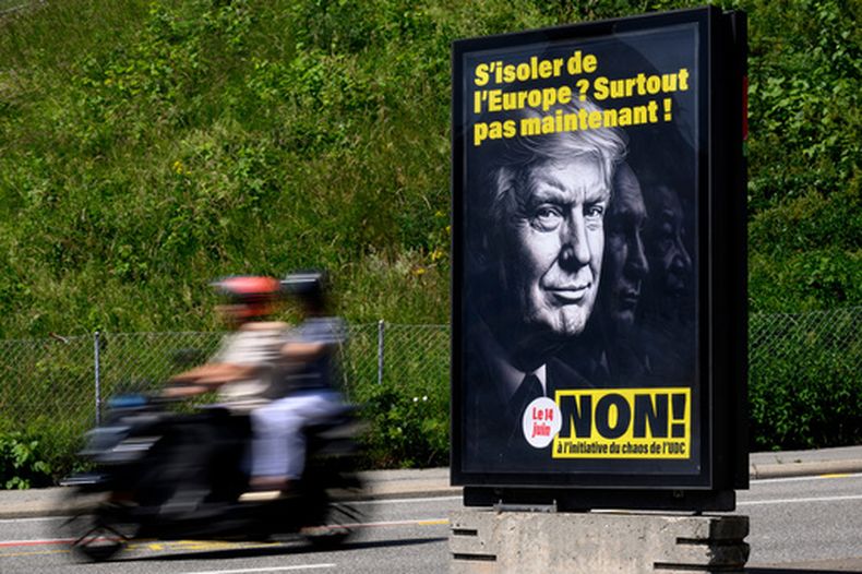 Un cartel con el mensaje ¿Aislarnos de Europa? ¡Desde luego ahora no! No a la iniciativa del caos de SVP/UDC, con las imágenes del presidente de Estados Unidos, Donald Trump; el presidente de Rusia, Vladímir Putin, y el presidente de China, Xi Jinping, para instar a la gente a votar contra la propuesta del Partido Popular Suizo (SVP) de limitar la población, en Lausana, el 27 de mayo de 2026. (Laurent Gillieron/Keystone via AP)