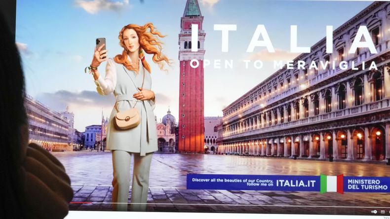 Unas personas observan un monitor con una campaña publicitaria del Ministerio de Turismo de Italia que muestra una versión digitalizada, y vestida, de la Venus del pintor renacentista Sandro-Botticelli, en Florencia. (AP Foto/Gregorio Borgia)