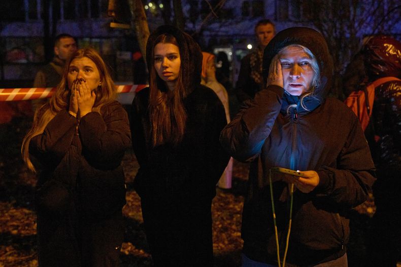 Vecinos reaccionan mientras ven arder su casa tras el impacto de un dron contra un edificio residencial de varias plantas, durante un ataque ruso en Kiev, Ucrania el martes 25 de noviembre de 2025. (AP foto/Efrem Lukatsky)
