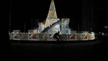 Un hombre monta una bicicleta frente a decoraciones de Navidad en una calle de Lagos, Nigeria, el viernes 20 de diciembre de 2024. (AP Foto/Sunday Alamba)