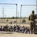ARCHIVO - Migrantes esperan junto a una valla fronteriza bajo la vigilancia de la Guardia Nacional de Texas el 10 de mayo de 2023 para ingresar a El Paso, Texas. (AP Foto/Andrés Leighton)