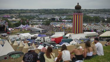 Asistentes sentados fuera de un bar durante el Festival de Glastonbury en Worthy Farm, Somerset, Inglaterra, el miércoles 25 de junio de 2025. (Scott A Garfitt/Invision/AP)