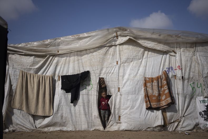 Una niña palestina, desplazada por la ofensiva terrestre de Israel en la Franja de Gaza, se asoma a una de las tiendas de un asentamiento improvisado en Rafah, el 23 de enero de 2024. (AP Foto/Fatima Shbair)