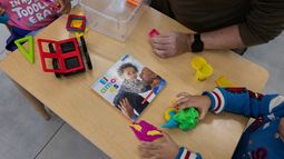 Una maestra y dos alumnos juegan con piezas de construcción magnéticas y pasta de modelar junto a un libro infantil titulado El amor es, en el John Cardinal OConnor Center for Parent and Child Development, un centro Head Start operado por The New York Foundling, en San Juan, Puerto Rico, el 13 de octubre de 2026. (AP Foto/Alejandro Granadillo)
