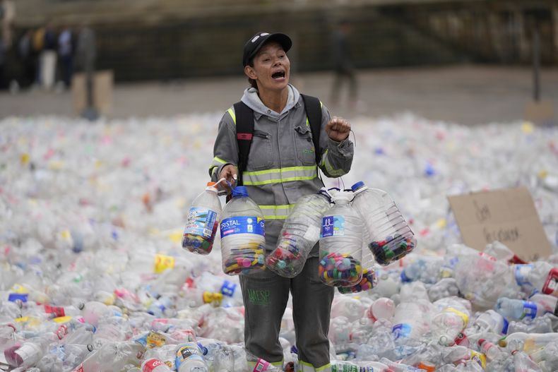 Un reciclador camina entre las botellas plásticas que cubren la Plaza Bolívar en Bogotá, Colombia, como parte de una protesta contra lo que los recicladores consideran un precio demasiado bajo que les pagan las empresas que compran materiales reciclados, el martes 24 de junio de 2025. (AP Foto/Fernando Vergara)