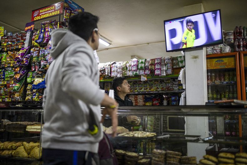Un cliente y el empleado de una cafetería observan el partido entre Colombia y Marruecos en el Mundial femenino, en las afueras de Bogotá, Colombia, el jueves 3 de agosto de 2023. (AP Foto/Iván Valencia)