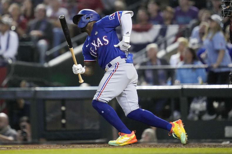 Adolis García, de los Rangers de Texas, se sujeta el costado izquierdo después de abanicar durante la octava entrada del Juego 3 de la Serie Mundial en contra de los Diamondbacks de Arizona, el lunes 30 de octubre de 2023, en Phoenix. (AP Foto/Godofredo A. Vásquez)