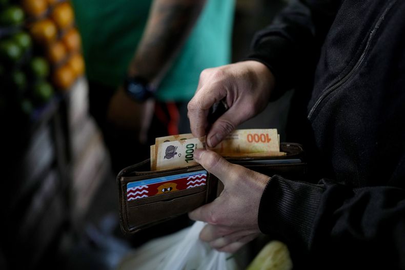 ARCHIVO - Un comprador sacando billetes de 1.000 pesos, en Buenos Aires, Argentina, el 1 de septiembre de 2023. Los artistas del movimiento argentino Money Art pintan billetes de la depreciada moneda y comparten su trabajo en redes sociales. Sus creaciones, entonces, se revalorizan alcanzando precios que van desde 40.000 a 70.000 pesos a nivel local y de hasta 300 dólares en el extranjero. (AP Foto/Natacha Pisarenko, Archivo)