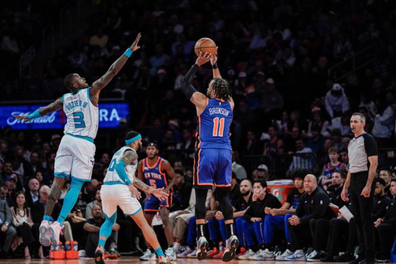 El escolta de los Knicks de Nueva York, Jalen Brunson (11), dispara a la canasta ante la defensa del escolta de los Hornets de Charlotte, Terry Rozier, durante la segunda mitad de un partido de baloncesto de la NBA en Nueva York, el martes 28 de noviembre de 2023. (Foto AP/Peter K. Afriyie)