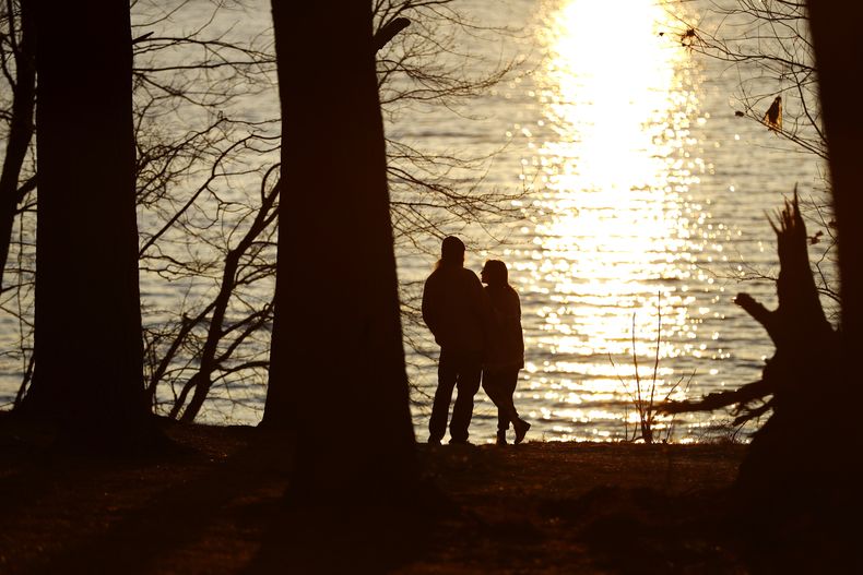 ARCHIVO - Una pareja a la orilla del embalse de Loch Raven mientras el sol comienza a ponerse, el 19 de febrero de 2020, en Glen Arm, Maryland. (Foto AP/Julio Cortez, archivo)