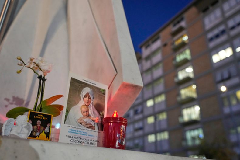 Una imagen del papa León XIV se ve apoyada en la base de un estatua del fallecido papa san Juan Pablo II delante de la Policlínica Agostino Gemelli, donde León está hospitalizado para una cirugía en el pulmón, en Roma, el martes 13 de octubre de 2026. (AP Foto/Gregorio Borgia)