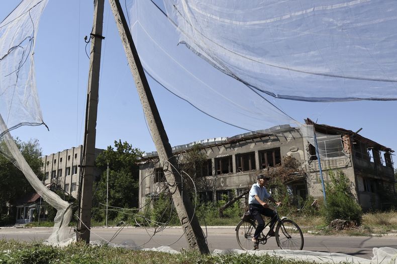 En esta imagen proporcionada por el servicio de prensa de la 65ta Brigada Mecanizada ucraniana, un vecino monta en bicicleta por una calle, bajo una red antidrones en Orikhiv, en la región de Zaporiyia, Ucrania, el martes 15 de julio de 2025. (Andriy Andriyenko/Servicio de prensa de la 65ta Brigada Mecanizada via AP)