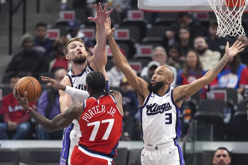 Kevin Porter Jr., base de los Clippers de Los Ángeles, envía un pase frente a Domantas Sabonis y Jordan McLaughlin (3), de los Kings de Sacramento, el viernes 22 de noviembre de 2024 (AP Foto/Mark J. Terrill)