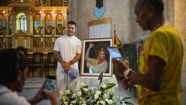 El reguetonero cubano Yomil posa junto a una imagen enmarcada de la fallecida cantante Celia Cruz tras asistir a una misa conmemorativa por el centenario de su nacimiento en la iglesia Virgen del Cobre o Nuestra Señora de la Caridad en La Habana, el martes 21 de octubre de 2025. (Foto AP/Ramon Espinosa)