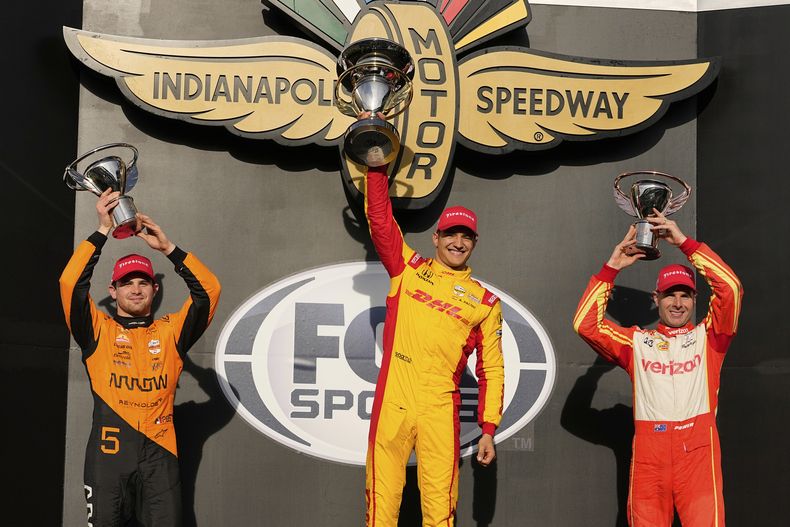 Alex Palou, de España, centro, celebra después de ganar la carrera de autos IndyCar Grand Prix en el Indianapolis Motor Speedway en Indianápolis, el sábado 10 de mayo de 2025. Pato OWard, de México, a la izquierda, terminó segundo y Will Power, de Australia, terminó tercero. (AP Foto/Michael Conroy)