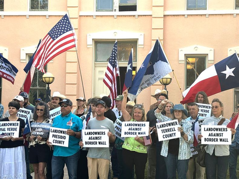 Propietarios de tierras y otros simpatizantes sostienen letreros contra los planes del gobierno de Trump de construir un muro fronterizo y otra infraestructura en la remota región de Big Bend, en Texas, el lunes 14 de septiembre de 2026, en Marfa, Texas. (AP Foto/Rebecca Santana)