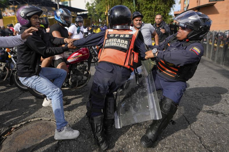 Un manifestante forcejea con la policía en las protestas contra los resultados de las elecciones que dieron por ganador a Nicolás Maduro, el día después de las votaciones en Caracas, Venezuela, el lunes 29 de julio de 2024. (AP Foto/Matías Delacroix)