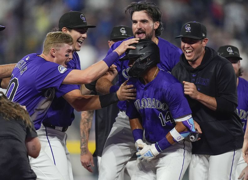 Ezequiel Tovar, de los Rockies de Colorado, al frente derecho, es felicitado después de conectar un sencillo productor de sus compañeros de equipo en la 12da entrada contra los Medias Rojas de Boston, el lunes 22 de julio de 2024, en Denver. (AP Foto/David Zalubowski)
