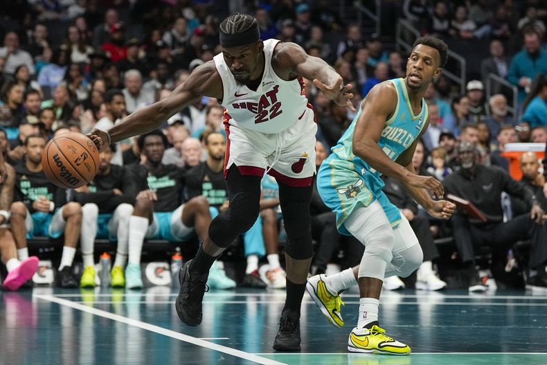 Jimmy Butler, del Heat de Miami, busca alcanzar la pelota, a un lado de Ish Smith, de los Hornets de Charlotte, el martes 14 de noviembre de 2023 (AP Foto/Chris Carlson)