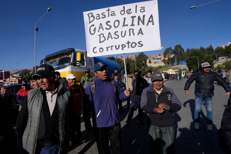 Conductores del transporte público protestan por la mala calidad de la gasolina; uno de ellos sostiene un cartel en el que se lee en español Basta ya de gasolina basura. Corrupción, en La Paz, Bolivia, el miércoles 25 de marzo de 2026. (Foto AP/Juan Karita)