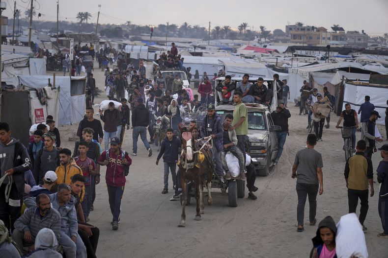 Palestinos llevan bolsas cargadas con comida y ayuda humanitaria proporcionada por la Fundación Humanitaria de Gaza, una organización con apoyo estadounidense autorizada por Israel, en Jan Yunis, en el sur de la Franja de Gaza, el martes 3 de junio de 2025. (AP foto/Abdel Kareem Hana)