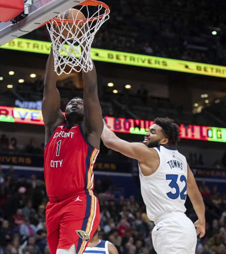 Zion Williamson (1), alero de los Pelicans de Nueva Orleans, deja atrás al pívot de los Timberwolves de Minnesota, Karl-Anthony Towns (32), para una clavada durante la primera mitad del juego de baloncesto de la NBA, el lunes 11 de diciembre de 2023, en Nueva Orleans. (David Grunfeld/The Times-Picayune/The New Orleans Advocate vía AP)