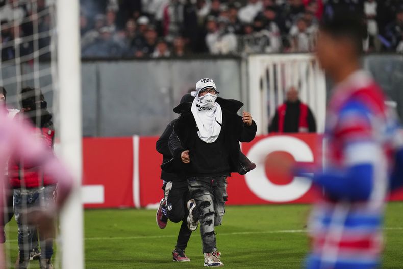 Un grupo de hinchas invade la cancha durante un partido de la Copa Libertadores entre Colo Colo de Chile y Fortaleza de Brasil, el jueves 10 de abril de 2025, en Santiago (AP Foto/Esteban Félix)