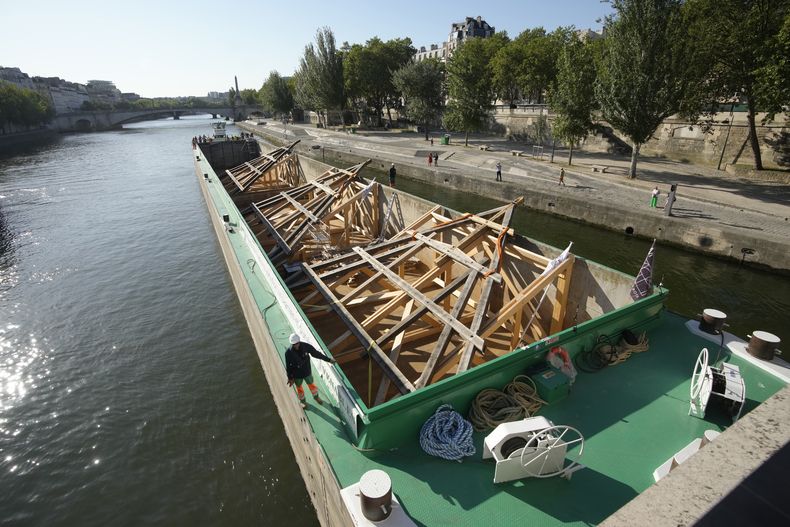 Una barcaza cargada con enormes marcos de roble llega cerca de la catedral de Notre Dame de París, el martes 11 de julio de 2023 en París. Los paneles se volverán a montar en la parte superior de Notre Dame para reemplazar el techo que las llamas convirtieron en cenizas en 2019. (Foto AP/Christophe Ena)