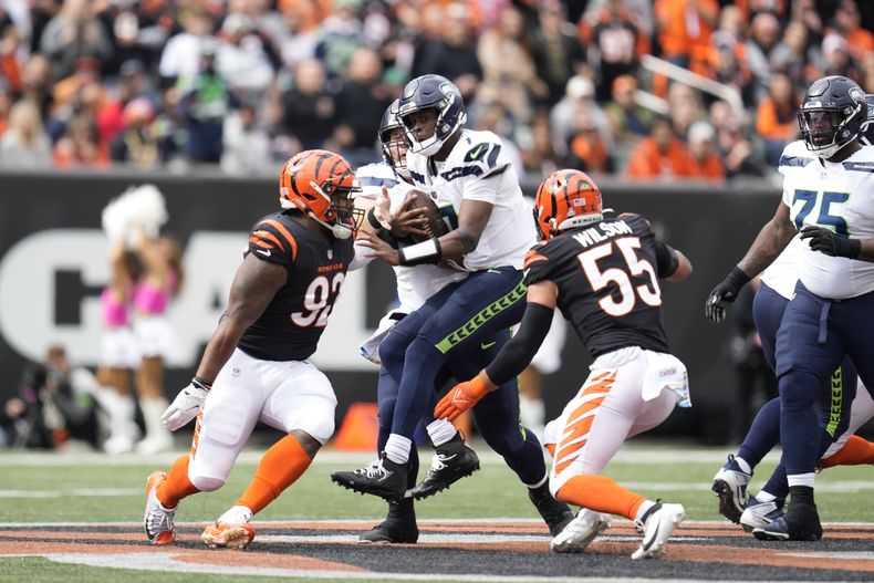 Geno Smith (7), quarterback de los Seahawks de Seattle, es capturado por Logan Wilson (55), de los Bengals de Cincinnati, durante la primera mitad del partido de la NFL, el domingo 15 de octubre de 2023, en Cincinnati. (AP Foto/Michael Conroy)