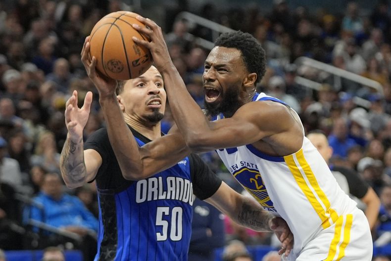 El armador del Magic de Orlando Cole Anthony (50) comete falta sobre el alero de los Warriors de Golden State Andrew Wiggins, que se dirigía a lanzar durante la segunda mitad del juego de baloncesto de la NBA, el miércoles 27 de 2024, en Orlando, Florida. (AP Foto/John Raoux)