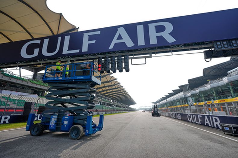 Unos trabajadores utilizan una plataforma de tijera para instalar una pancarta sobre la pista antes del Gran Premio de Bahrein en Malasia, en el Circuito Internacional de Sepang, el miércoles 30 de septiembre de 2026, en Sepang, Malasia. (Foto AP/Vincent Thian)