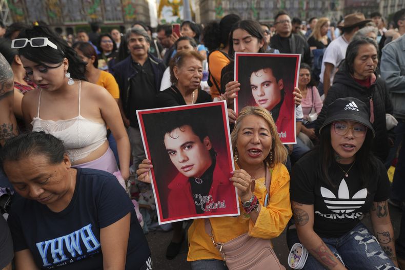 Fans de Juan Gabriel con afiches previo a una proyección de uno de sus conciertos en el Zócalo, la plaza principal de la Ciudad de México, el domingo 22 de septiembre de 2024. (Foto AP/Fernando Llano)