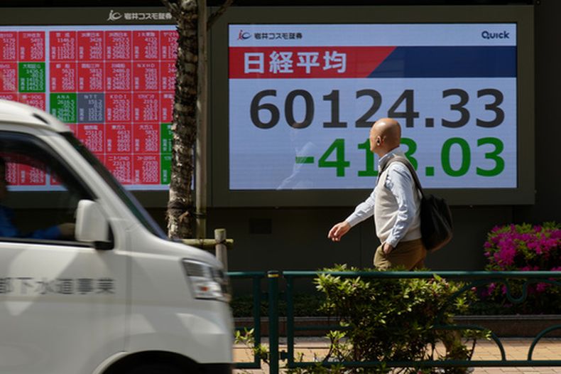 Una persona camina ante una pantalla con el índice bursátil Nikkei de Japón en la fachada de una correduría, el martes 28 de abril de 2026 en 2026, en Tokio. (AP Foto/Eugene Hoshiko)