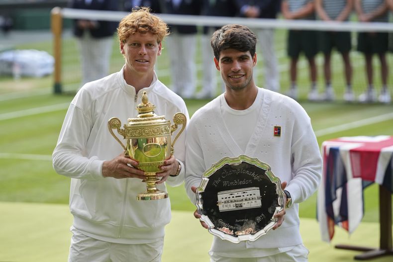 ARCHIVO - Jannik Sinner (izquierda) sostiene su trofeo de campeón tras derrotar a Carlos Alcaraz (derecha) en la final del torneo de Wimbledon, el 13 de julio de 2025, en Londres. (AP Foto/Kin Cheung)