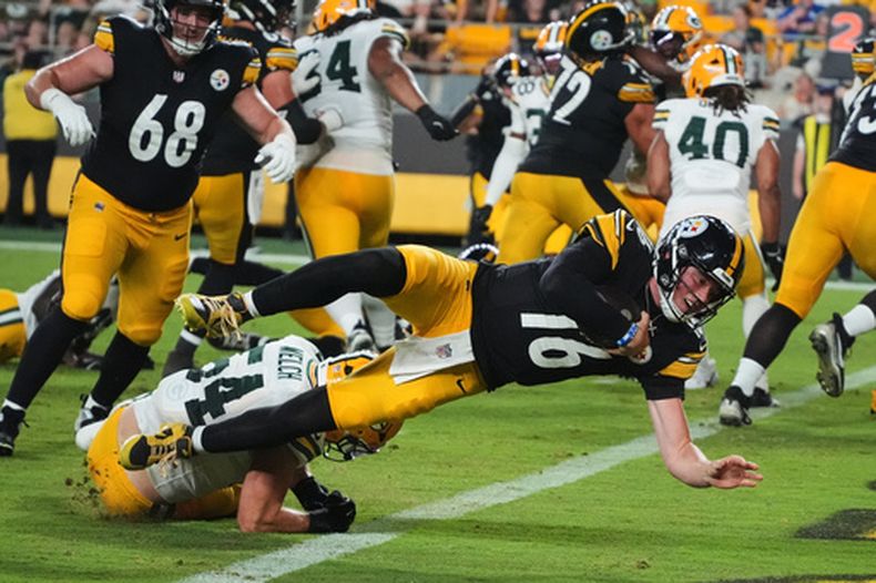 Drew Allar (16), quarterback de los Steelers de Pittsburgh, se lanza sobre el linebacker Kristian Welch, de los Packers de Green Bay, hacia la zona de anotación en una posesión ofensiva en la segunda mitad del partido de pretemporada de la NFL, el jueves 13 de agosto de 2026, en Pittsburgh. (AP Foto/Gene J. Puskar)