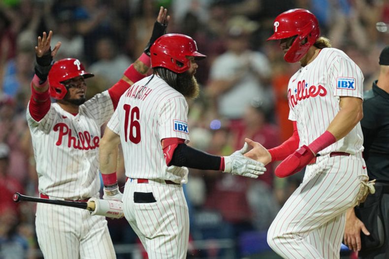 Luis Arraez, de los Filis de Filadelfia, y Alec Bohm, a la derecha, celebran con Brandon Marsh (16) después de anotar un doble hit por Bryson Stott de los Filis durante la sexta entrada del juego de béisbol contra los MArlins de Miami el martes 18 de agosto de 2026, en Filadelfia. (AP Photo/Matt Rourke)