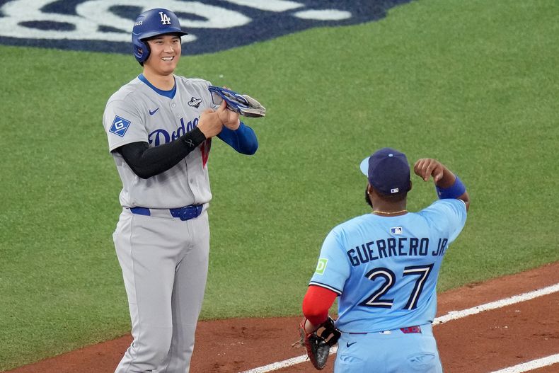 El japonés Shohei Ohtani, de los Dodgers de Los Ángeles, y el dominicano Vladimir Guerrero Jr., de los Azulejos de Toronto, bromean luego que el primero recibió una base por bolas en el sexto juego de la Serie Mundial, el viernes 31 de octubre de 2025 (Chris Young/The Canadian Press via AP)