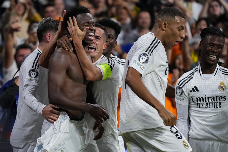 Vinicius Junior celebra con sus compañeros tras anotar el cuarto gol del Real Madrid en la victoria 5-2 ante Borussia Dortmund en la Liga de Campeones, el martes 22 de octubre de 2024, en Madrid. (AP Foto/Manu Fernández)