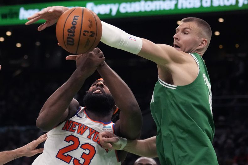 El pívot Kristaps Porzingis, derecha, de los Celtics de Boston, bloquea un tiro de Mitchell Robinson (23), de los Knicks de Nueva York, durante la segunda mitad del juego de baloncesto de la NBA, el viernes 8 de diciembre de 2023, en Boston. (AP Foto/Charles Krupa)
