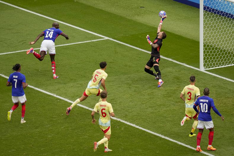 El arquero de España Arnau Tenas salva un cabezazo de Jean-Philippe Mateta de Francia, segundo a la izquierda, durante el partido por la medalla de oro en el fútbol de los Juegos Olímpicos en el estadio Parque de los Príncipes, el viernes 9 de agosto de 2024, en París, Francia. (AP Foto/Vadim Ghirda)