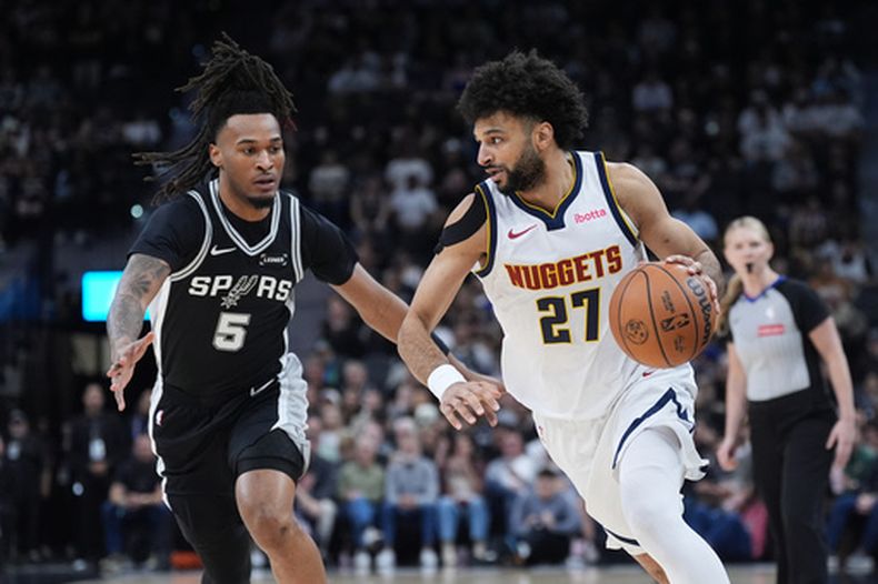 El base de los Nuggets de Denver Jamal Murray avanza con el balón hacia la canasta ante el base de los Spurs de San Antonio Stephon Castle el jueves 12 de marzo del 2026. (AP Foto/Eric Gay)