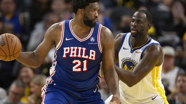 El pívot de los 76ers de Filadelfia Joel Embiid observa antes de pasar el balón mientras lo defiende el alero de los Warriors de Golden State Draymond Green en el encuentro del martes 30 de enero del 2024. (AP Foto/D. Ross Cameron)