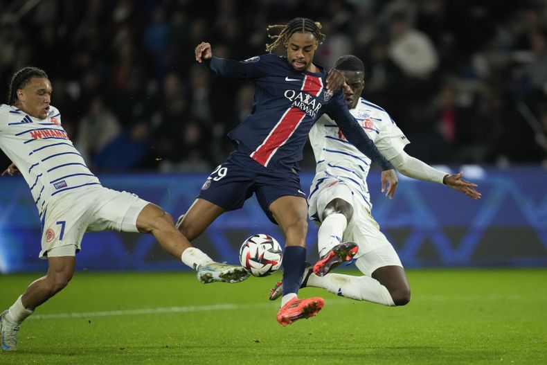 Bradley Barcola, centro, del PSG, es cubierto por Mamadou Sarr, derecha, y Diego Moreira, del Estrasburgo, durante el partido de fútbol de la League One francesa entre el Paris Saint-Germain y el Estrasburgo en el Parque de los Príncipes de París, el sábado 19 de octubre de 2024. (AP Foto/Christophe Ena)