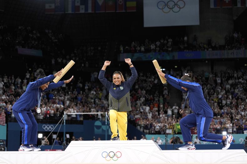 La medalllista de plata Simone Biles (izquierda) y la medallista de bronce Jordan Chiles se inclinan ante la campeona brasileña Rebeca Andrade tras ganar la medalla de oro en el ejercicio de piso de los Juegos Olímpicos de París, el lunes 5 de agosto de 2024. (AP Foto/Abbie Parr)