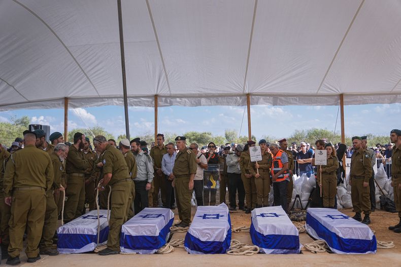 Varias personas se congregan en torno a los ataúdes de cinco miembros de la familia Kotz durante su funeral en Gan Yavne, Israel, el 17 de octubre de 2023. La familia fue asesinada por insurgentes de Hamás el 7 de octubre en su casa en el kibutz de Kfar Azza, cerca de la frontera con la Franja de Gaza. Más de 1.400 personas fallecieron, en su mayoría civiles israelíes, y unas 240 fueron capturadas en un ataque transfronterizo sin precedentes lanzado por el grupo insurgente que gobierna la Franja. (AP Foto/Ohad Zwigenberg)